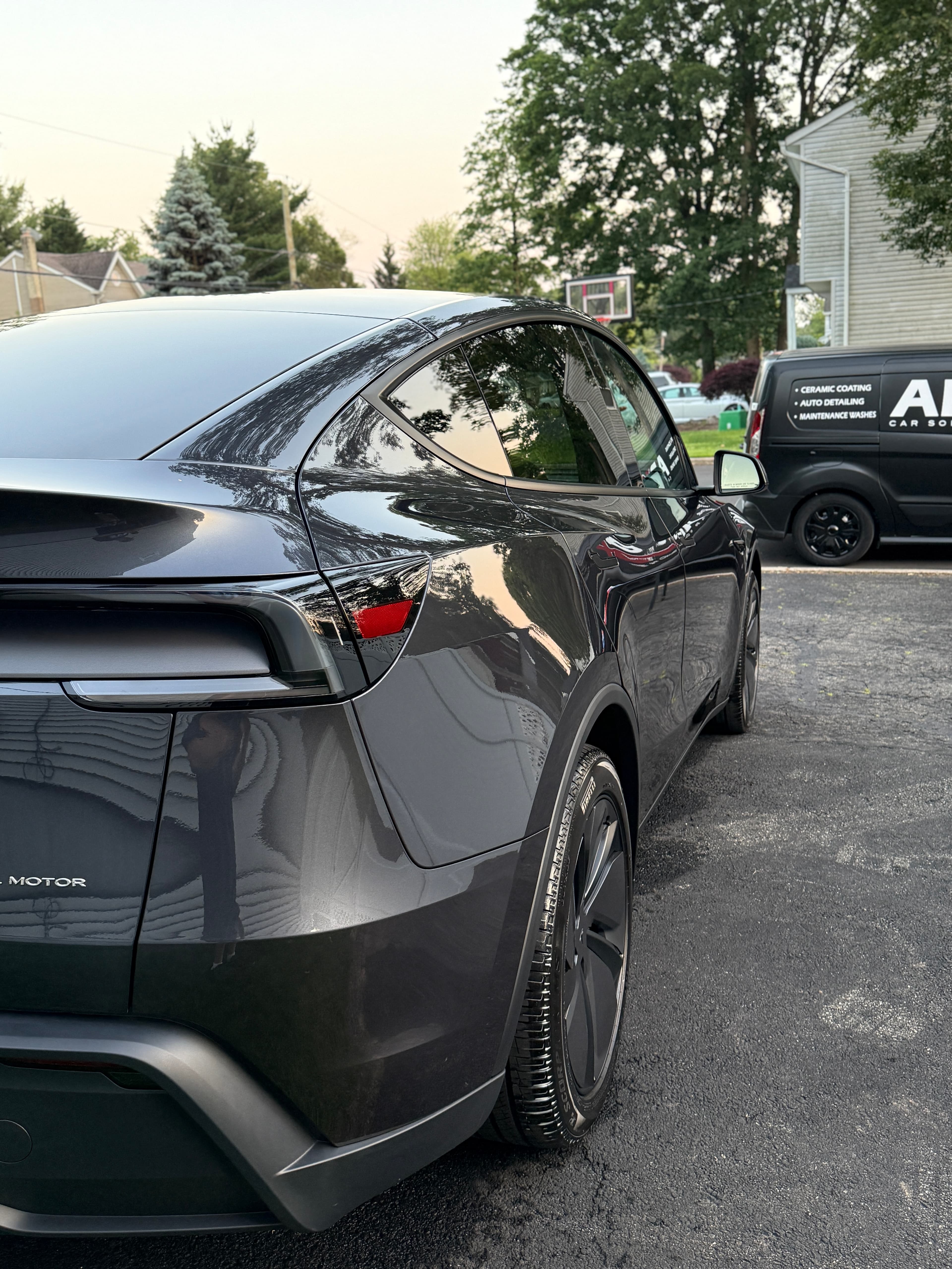 Gray Tesla Model Y freshly detailed in a New Milford driveway with the APX van on site